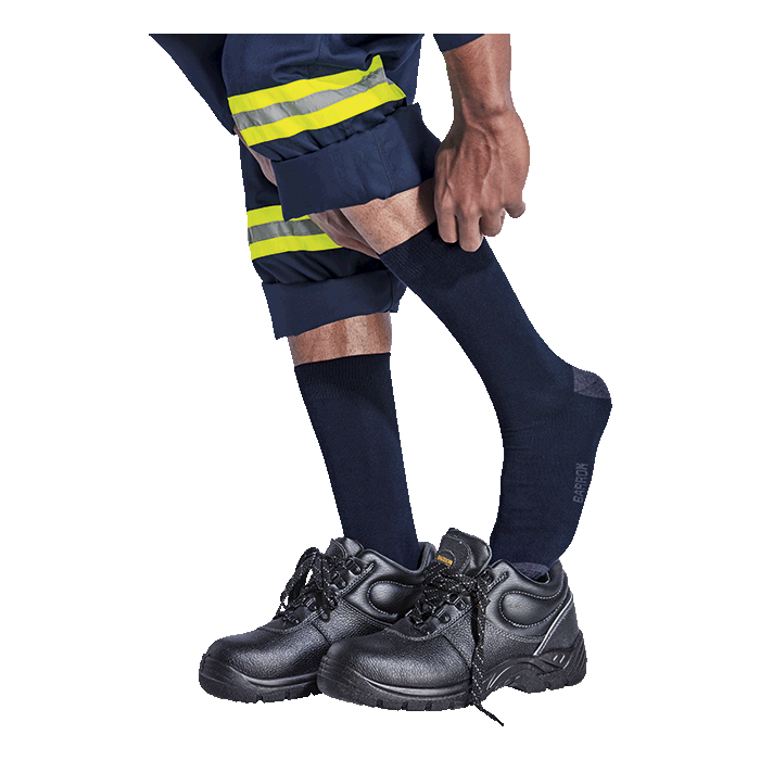 Person wearing black safety shoes, navy socks, and reflective safety pants on a white background